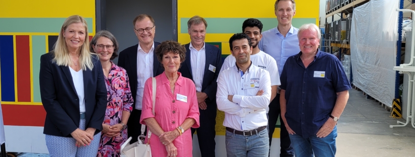 Gruppenbild in der Temps-Ausbildungshalle mit Daniel Terzenbach, Johannes Pfeiffer, deren Begleitung und dem temps-team vor einer bunten Wand