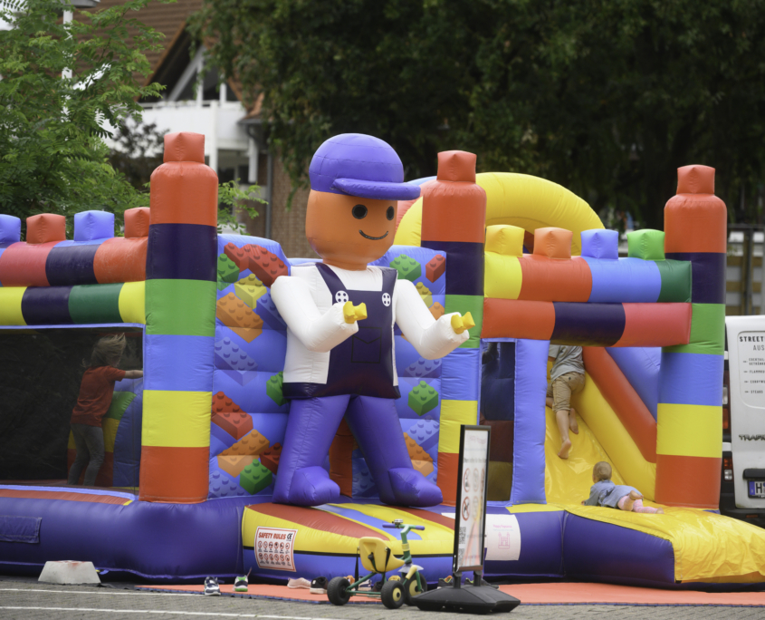 Eine bunte Lego-Hüpfburg auf einem Firmengelände im Rahmen von einem Sommerfest