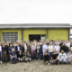 Gruppenbild der Neustädter Belegschaft auf dem Sommerfest vor dem alten Lager und einer gelben Wand