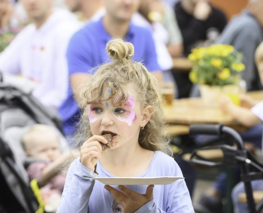 Ein geschminktes Kind isst ein Stück Kuchen