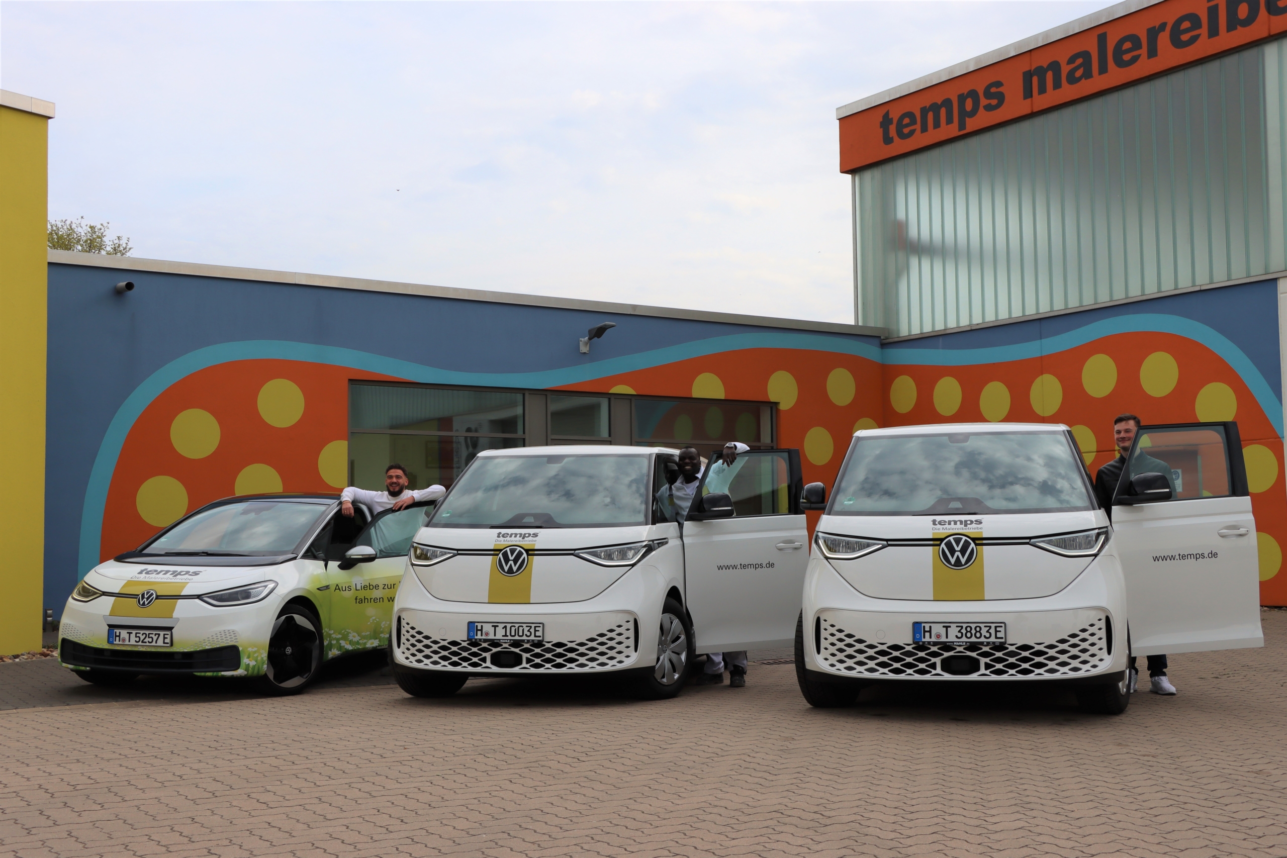 Drei Vollstromer von VW vor einer bunten Wand einer Industriehalle