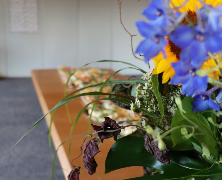 Ein Blumenstrauss auf einem mit Brötchenplatten gedeckten Tisch zum Jubiläum von Elke Pielorz