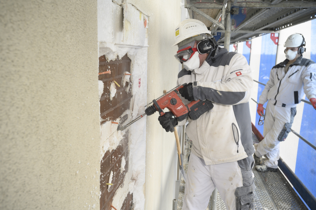 Ein Mitarbeiter arbeitet am Rückbau der Fassade