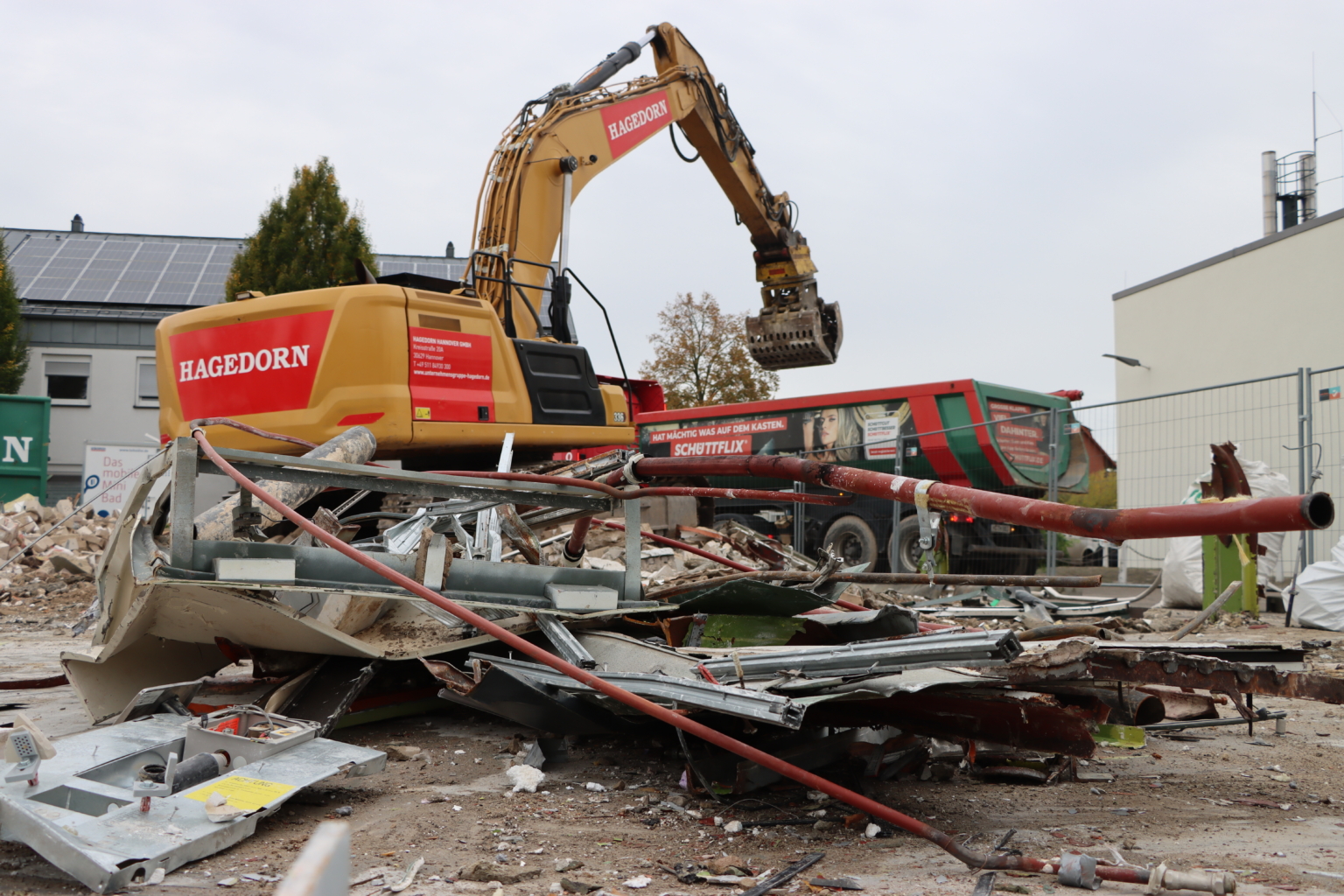 Ein Bager sortiert Schrott, welcher beim Abriss entstanden ist